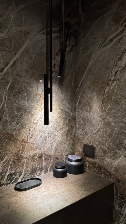 Baño moderno con paredes de mármol, iluminación colgante y dos frascos oscuros — proyecto CASA MHN, por Hermann Arquitectos, en Nordelta